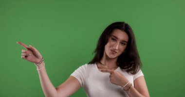 Esmer bir kadının yeşil arka planda bir tarafı gösteren bir stüdyo fotoğrafı. Bu görüntü moda ve güzellik ürünü reklamları ve pazarlama kampanyaları için uygundur..