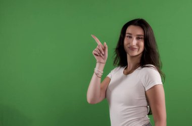 Esmer bir kadının yeşil arka planda yukarı doğru bakan bir stüdyo fotoğrafı. Bu görüntü moda güzellik ürünleri modelleri ve reklam kampanyaları için uygundur..