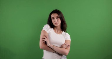 Stüdyo portresi, beyaz bluzlu, kolları yeşil arka planda olan esmer bir kadının portresi. Bu görüntü moda güzelliği ve yaşam tarzı projeleri için uygundur..