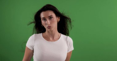 Yeşil arka planda dalgalı saçları olan güzel esmer bir kadının stüdyo portresi. Bu görüntü moda güzelliği ve reklam projeleri için uygundur..