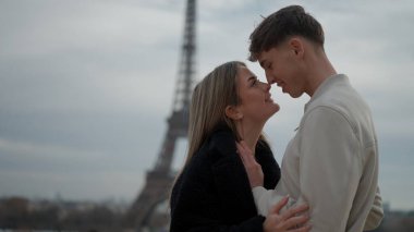 Paris 'te, arka planda Eyfel Kulesi olan romantik bir çift Fransa' yı kucaklıyor. Bu resim seyahat turizmi ve Avrupa tatil kavramları için uygundur..