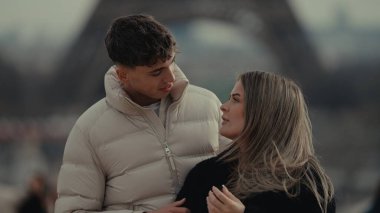 Arka planda Eyfel Kulesi ile Paris 'te romantik bir çift kucaklaşıyor. Genç adam ve kadın, Avrupa seyahatlerinin ve turizm deneyimlerinin tadını çıkarıyorlar..