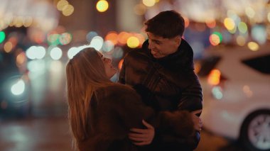 Romantik bir çift gece Paris 'te sarılır. Etrafı bokeh ışıkları ve araba farlarıyla çevrilidir. Şehir içi romantizm ve seyahat teması için mükemmel bir şehir ortamında sevgi ve şefkat görüntülenir..