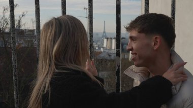 Paris 'te arka planda görünen Eyfel Kulesi ile kucaklaşan genç bir çift görülüyor. Bu resim seyahat romantizmi ve yaşam tarzı kavramları için mükemmeldir..