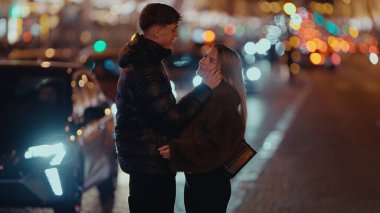 Romantik bir çift, arka planda Bokeh ışıkları ve arabalarla Paris 'te bir sokakta sarılıyor. Bu görüntü Fransa 'da aşk ve sevgi aktarımı şehir romantizmi kavramları ve seyahat temaları için idealdir.