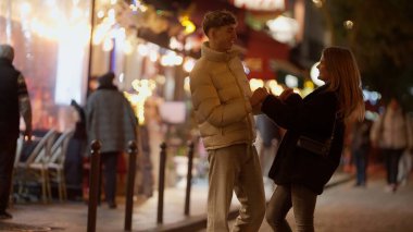 Genç bir çift gece Paris sokaklarında Bokeh ışıkları altında el ele tutuşuyor. Bu görüntü, Fransa 'da bir şehir ortamında aşkın romantizmini ve bağlantısını yakalar..