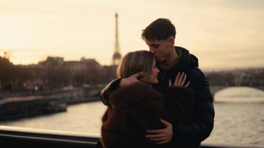 Romantik bir çift gün batımında Paris 'te arka planda Eyfel Kulesi' ne sarılır. Bu resim seyahat turizmi romantizmi veya Avrupa tatil kavramları için kullanılabilir..