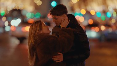 Romantik bir çift, Paris 'te gece vakti sarılır. Etrafı bokeh ışıklarıyla çevrilidir. Görüntü, sevgiyi ve Avrupa tatilinin cazibesini taşır..