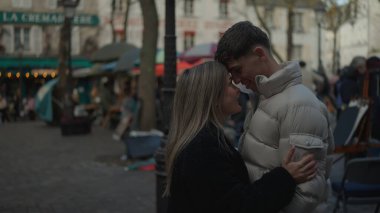 Romantik bir çift Montmartre Paris 'te sevgi ve şefkat dolu bir anı paylaşıyor. Avrupa şehir manzarasında kışlık palto giyiyorlar. Seyahat ve turizmle ilgili içerik için ideal..