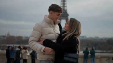 Paris 'te arka planda Eyfel Kulesi ile kucaklaşan genç bir çift, Avrupa' da popüler bir tatil beldesinde romantik seyahat ve şehir yaşam tarzını sergiliyor..