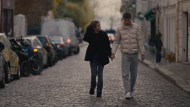 Romantik bir çift, Paris 'te sonbahar sezonu boyunca kaldırım taşlı bir sokakta el ele yürür. Görüntü, seyahat yaşam tarzı veya ilişki içeriği için uygun bir şehir ortamında bir aşk ve bağlantı anı yakalar..