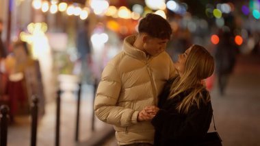 Paris 'te romantik bir çift, gece Fransa' da Bokeh ışıklarıyla sıcak ve davetkar bir atmosfer yaratıyor. Bu resim seyahat ilişkileri ve yaşam tarzı içeriği için uygundur.