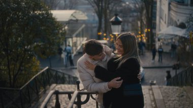Genç bir çift Paris 'te Montmartre' nin merdivenlerinde kucaklaşır ve samimi bir anı paylaşır. Bu resim, aşk seyahatini ve şehir ilişkilerinin güzelliğini aktarıyor..