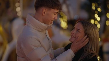 Romantik bir çift, kış mevsiminde Paris 'te Noel pazarı ışıkları yakınında sevgi ve şefkat ile kucaklaşır. Bu resim Sevgililer Günü ve diğer romantik durumlar için mükemmel..