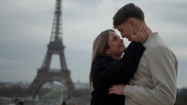 Romantik bir çift Paris 'te Fransa' da Eyfel Kulesi 'nin arka planında bulutlu bir günde sarılır. Bu seyahat fotoğrafçılığı turizm ve romantizm kavramları için mükemmel..