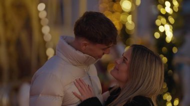 Romantik bir çift, Paris 'te Noel ışıklarının arka planıyla sarılır. Genç aşıklar, kış tatili boyunca bir sevgi ve şefkat anlarını paylaşırlar..