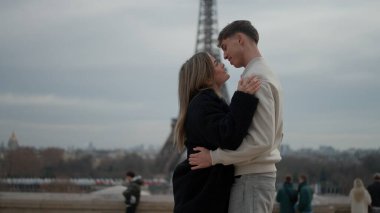 Romantik bir çift Paris 'te Fransa' da Eyfel Kulesi 'nin arka planında bulutlu bir günde sarılır. Bu resim seyahat turizmi ve ilişki kavramları için uygundur.