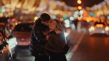 Romantik bir çift, geceleri Paris 'te bir sokakta sarılır. Arka planda Bokeh ışıkları ve şehir manzarası vardır. Bu resim Sevgililer Günü kutlamaları veya seyahat içeriği için uygundur.