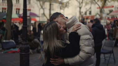 Genç bir çift, Montmartre Paris 'te sevgi dolu bir şekilde kucaklaşır. Görüntü, şehir ortamında seyahat ve ilişki teması için ideal aşıklar arasında romantik bir an yakalar..