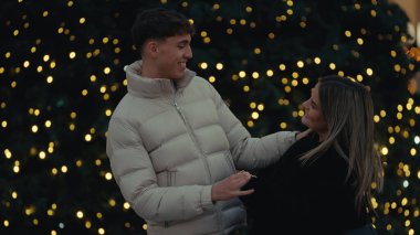 Genç bir çift, Paris 'te romantik bir anda sarılıyor. Arka planda Noel ışıkları var. Bu resim, aşk seyahati ve tatil sezonunu resmetmek için mükemmel..