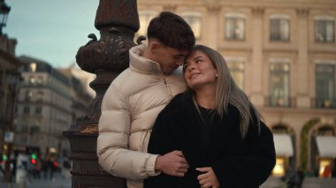 Romantik bir çift, Paris 'te bir sokak lambasının yanında sevgi ve şefkat dolu bir anı paylaşıyor kışlık paltolar giyiyorlar ve güzel Avrupa şehir manzarasında tatilin tadını çıkarıyorlar..