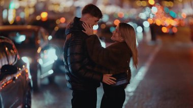Romantik bir çift gece Paris 'te bir sokakta sarılır ve etrafı bokeh ışıklarıyla çevrilidir. Bu görüntü, Fransa 'da seyahat turizmi ve şehir romantizmi için ideal sevgi ve sevgiyi yakalıyor..