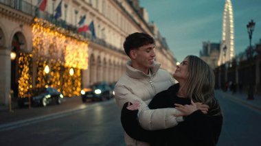 Romantik bir çift, alacakaranlıkta Paris sokaklarında Eyfel Kulesi 'nin arka planında görünür bir şekilde sarılır. Bu resim, Fransa 'da aşk bağlantısını, seyahat ve turizmin cazibesini aktarıyor..