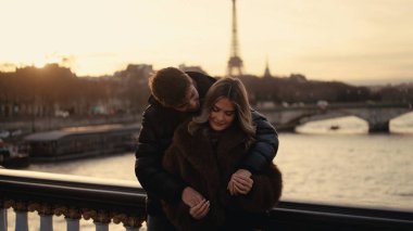 Romantik bir çift gün batımında Paris 'te arka planda Eyfel Kulesi' ne sarılır. Bu resim seyahat turizmi ve stok fotoğrafçılığı için uygundur..