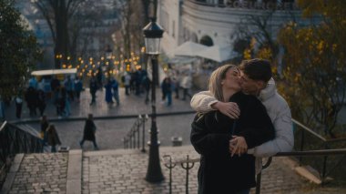 Romantik bir çift Paris 'te Montmartre' nin merdivenlerinde öpüşüyor. Fransa 'da şehir manzarası ve arka planda sonbahar ağaçları var. Bu resim seyahat romantizmi ve yaşam tarzı kavramları için kullanılabilir.