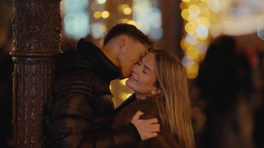 Romantik bir çift, gece Paris 'te bir lamba direğinin yanında sarılır. Bu görüntü, şehir ortamında seyahat yaşam tarzı ve ilişki teması için uygun bokeh ışıkları olan bir aşk ve şefkat anı yakalar..