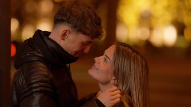 Genç bir çift Paris 'te geceleri Fransa' da sarılıyor ve arka planda Bokeh ışıkları var. Bu görüntü, bir Avrupa şehrinde sevgi dolu bir şehir romantizmi anını yakalar..