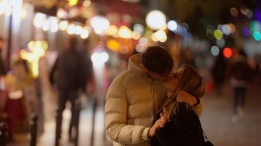 Paris 'te romantik bir çift, gece Fransa' da etrafı bokeh ışıklarıyla çevrili. Bu görüntü, şehir ortamında sevgi, seyahat ve ilişkilerin neşesini taşır..