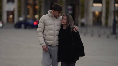 Genç bir çift, bir Paris caddesinde sevgi dolu bir bakışla kucaklaşırken görüntüler, Avrupa şehrinde şehir turizmi romantik ilişkilerini ve şık kış modasını gözler önüne seriyor..