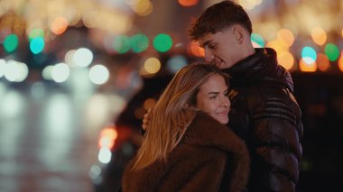 Romantik bir çift gece Paris 'te sarılır. Arka planda bokeh ışıkları olan genç adam ve kadın birbirlerine aşık olurlar. Şehir ışıklarıyla sıcak ve sevgi dolu bir şehir manzarası yaratırlar..