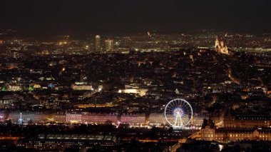 PARIS, FRANCE - 16 ARALIK 2025 - Paris geceleri gökyüzü, şehrin mimarisini aydınlık Sacre Cour ve dönme dolap ile gösteriyor