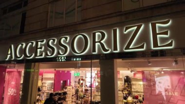 LONDON, UK - 8 HAZİRAN 2026 - Dükkan vitrininde neon ışığı ve moda aksesuarları, satışlar