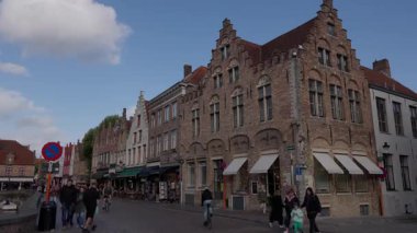 BRUGES, BELGIUM - 15 Eylül 2025 - Bruges 'de canlı bir cadde boyunca yürüyen insanlarla geleneksel Flaman binaları