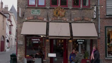 BRUGES, BELGIUM - 15 Eylül 2025 - Bruges 'de tarihi bir kaldırım taşı caddesinde açık havada oturan rahat bir kafe