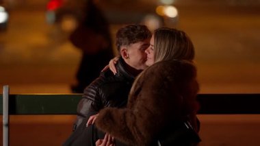 Romantik bir çift gece Paris 'te bir bankta kucaklaşır. Sahne sığ bir alan derinliği ve derin bir arka plan ile sıcacık bir aşk ve şefkat anı yakalar..