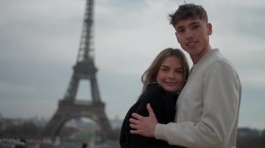 Genç bir çift Paris 'te Eyfel Kulesi' nin önünde kucaklaşır. Fransa 'da romantik bir portre, aşıklar arasındaki sevgiyi bulutlarda yakalar..