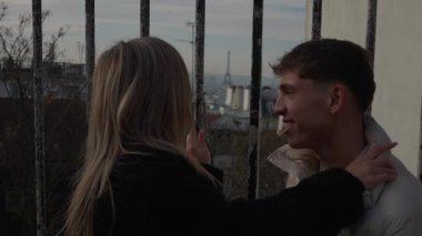 Romantik bir çift, Paris 'te arka planda görünen Eyfel Kulesi' ni kucaklıyor. Genç bir kadın, manzaralı bir manzaranın ardından bir erkeğe sarılıyor..