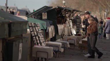 Paris 'teki Seine Nehri' nde yürüyen bir çift buketleri karıştırıyor. El kamerasıyla aşk şehrinde romantik bir yürüyüş çekiliyor. İnsanlar güneşli bir günün tadını çıkarıyor..