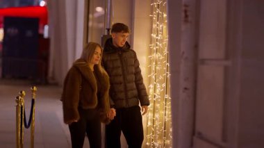 Genç bir çift gece Paris 'te vitrinlere bakıyor. Kadın ve erkek aydınlanmış bir gösteriye bakıyor. Bu klip Avrupa 'da romantik bir günü yavaş çekimde yakalıyor..