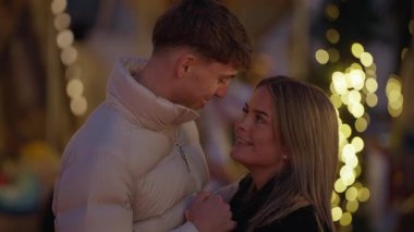 Genç bir çift Paris 'te el ele tutuşup birbirlerine bakarlar. Fransa' da geceleri Bokeh ışıkları romantik bir ortam yaratır. Orta ölçekli el kamerası..