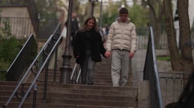Montmartre Paris 'te genç bir çift merdivenlerden aşağı inerken elde taşınan fotoğraf, birlikte şehri keşfederken romantik yürüyüşü yakalıyor..