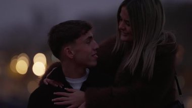 Genç bir çift, Paris 'te, alacakaranlıkta romantik bir şekilde kucaklaşır kadın, erkeğin, şehir ışıklarının bulanık arka planına karşı sevgiyle sarılır..