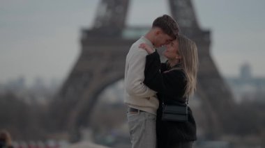 Paris 'te Eiffel Kulesi' nin arka planında romantik bir çift kucaklaşır..
