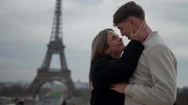 Paris 'te genç bir çift Eiffel Kulesi' ni arka planda görüp kucaklaşır. Aşıklar aşk şehrinde sevgi ve yakınlık gösteren hassas bir anı paylaşırlar..