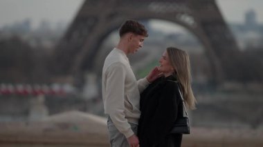 Paris 'te, arkasında Eyfel Kulesi olan sevgi dolu bir çift şehrin kalbinde kadının şefkatini ve romantizmini nazikçe ifade eder..