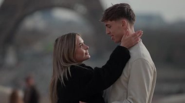 Paris 'te, Fransa' da Eyfel Kulesi 'nin yanında romantik bir çift erkeğin sığ yüzeyine dokunur ve yumuşak, samimi bir ortam yaratır..